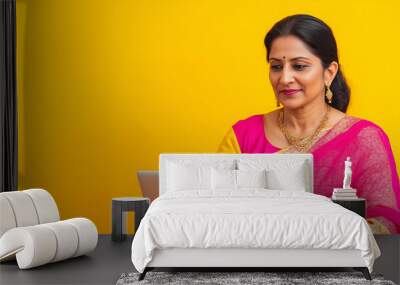 Confident woman in a vibrant pink saree working on a laptop, representing modern technology use while embracing cultural attire.
 Wall mural