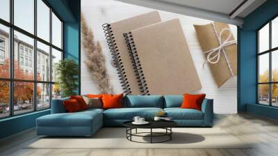 Mockup composition with two spiral notebooks with kraft paper covers, gift present and fluffy dry plant o n white background. Wall mural