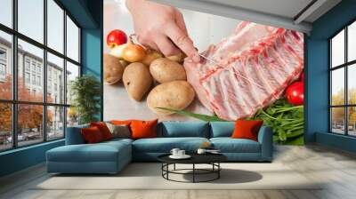 Cook hands with raw meat and vegetables in kitchen Wall mural