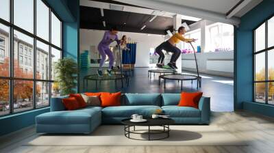 Group of happy women warming up before training in   gym jumping on   trampoline Wall mural