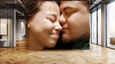 Emotional portrait of affectionate smiling kissing couple, close-up view Wall mural