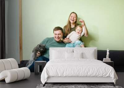 Young happy family with little toddler kid and pets dog and cat at home on the couch Wall mural