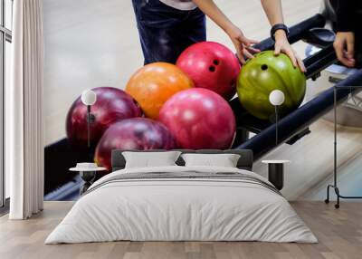 Children's hands taking ball from bowling balls machine Wall mural