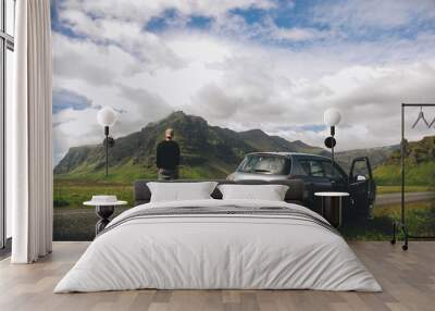 Man standing next to his car in the mountains Wall mural