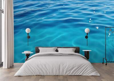 A serene view of clear blue water with gentle ripples and light reflections. Wall mural