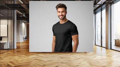 A smiling man wearing a plain black t-shirt against a grey background. Wall mural