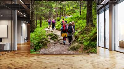 Young hikers in forest heading towards High Tatras peak Wall mural