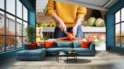 Front view of female hands making salad cutting tomatoes in the kitchen Wall mural