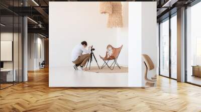 Male photographer working in minimal light and airy interior , white and beige chair, rug and pillows Wall mural