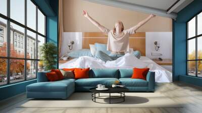 Woman stretching in bed after wake up Wall mural