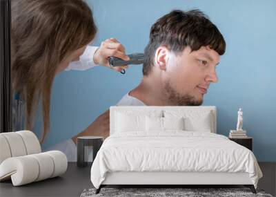 young male patient testing hearing aid in clinic exam room, female doctor helping Wall mural