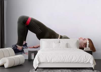 Young sportive woman doing a glute bridge isolated on gray background Wall mural