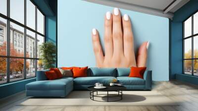 Young woman hands with white nails on light blue background. AI Generated Wall mural