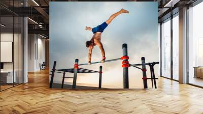 fitness, sport, training, calisthenics and lifestyle concept - young man exercising handstand on bar outdoors Wall mural