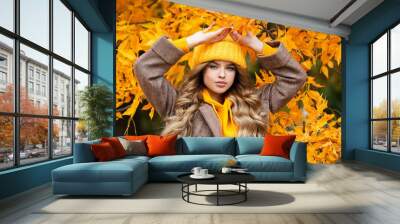 Beautiful girl walking outdoors in autumn. Smiling girl collects yellow leaves in autumn. Young woman enjoying autumn weather. Wall mural