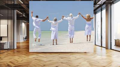 four people, two seniors, family couples, jumping on beach Wall mural