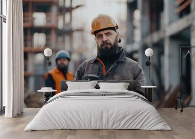 Bearded engineer on construction site with coworkers and phone. Wall mural