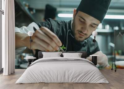 Closeup of a concentrated male chef garnishing food in the kitchen Wall mural