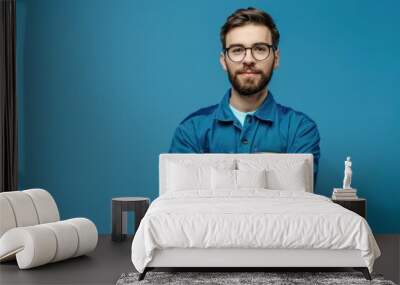 Confident young man in blue workwear shirt and glasses. Wall mural