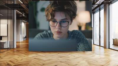 Non binary person using laptop with serious expression  looking natural. Wall mural