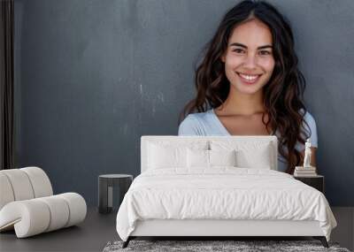 Smiling Latin woman with crossed arms on grey wall. Wall mural