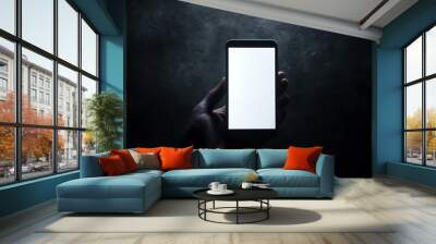 A mobile phone with a white screen held by a person in a dark room, with only the phone illuminated Wall mural