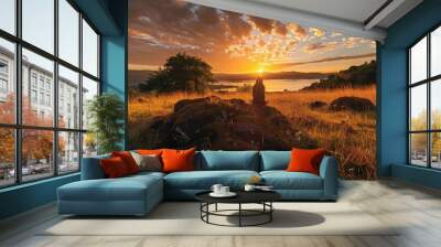 A person stands quietly amidst a golden landscape as the sun rises over a sacred site, casting warm light on the tranquil surroundings Wall mural