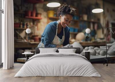 Beautiful african woman holding pottery instrument for scraping, smoothing, shaping and sculpting. Lady siting on bench with pottery wheel and making clay pot (generative ai) Wall mural