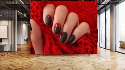 Close up womans hand with halloween manicure on red background holding fabric. Manicure, pedicure beauty salon concept Wall mural