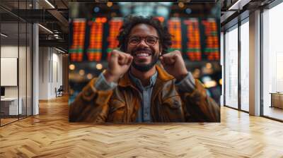 Joyful investor celebrates success against a backdrop of stock market boards Wall mural