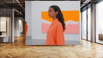 Two models in orange suits walk through a gallery with abstract art, their expressions serious Wall mural