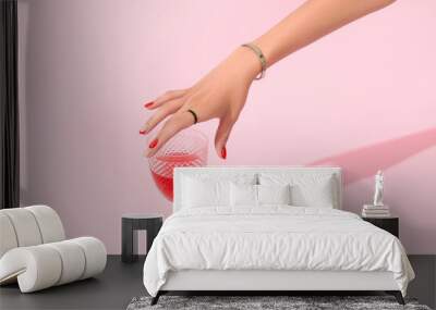 Womans hand holding glass on pink background. Manicure design trends Wall mural