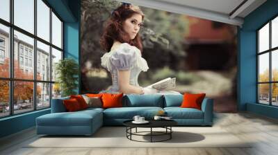 beautiful girl in historical dress, gloves, with a book in her hands sitting on the bench Wall mural