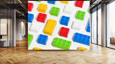 Angled view of many plastic colored pattern rainbow building toy brick blocks on white isolated background. The concept of educational games. Background for your design Wall mural