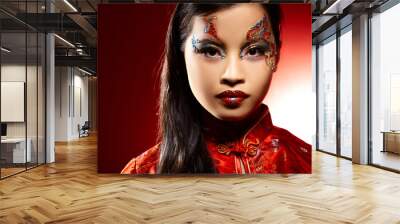 Beautiful Asian girl as a plastic doll on red background Wall mural