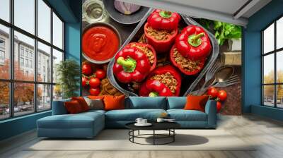 Red bell stuffed paprika peppers in iron cooking pot with various ingredients on side Wall mural