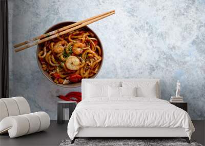 Traditional asian udon stir-fry noodles with shrimp in bowl and chopsticks. Fresh chilli pepers on side. Placed on bright stone background with copy space. Wall mural