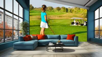 Cute little girl playing golf on a field outdoor Wall mural