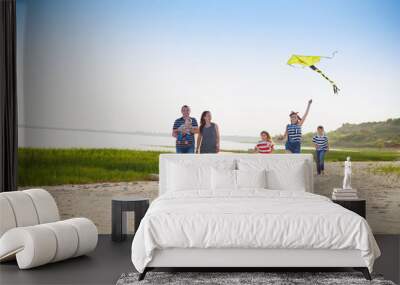 Happy young family with flying a kite on the beach Wall mural