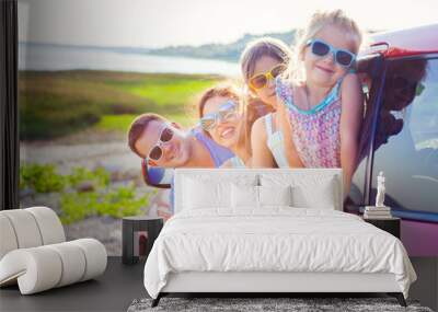 Portrait of a smiling family with two children at beach in the car Wall mural