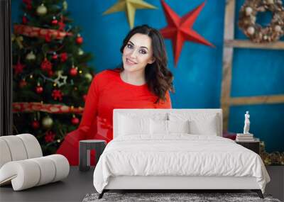 Smiling happy woman with gift box over living room on Christmas tree background Wall mural