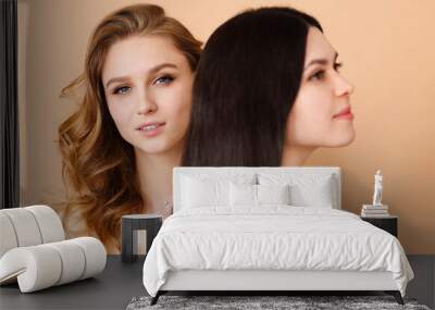 Two beautiful multicultural young women over beige background Wall mural