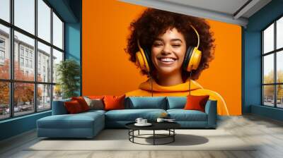 Funny cheerful young Hispanic girl with headphones listening to music on an orange background. Generative ai. Wall mural