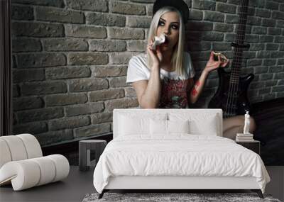 Young European teenage brunette  model ,  wearing blue jeans mini shorts, sneakers, and white t-shirt and a cap, eating pizza Wall mural