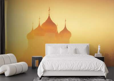 Golden domes in fog in sunlight as background. Winter frosty misty morning. Church in fog in background of rising sun. Wall mural