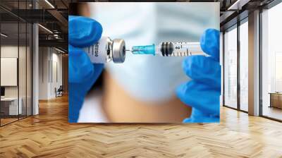 Healthcare worker in blue gloves prepares a syringe with a vaccine Wall mural