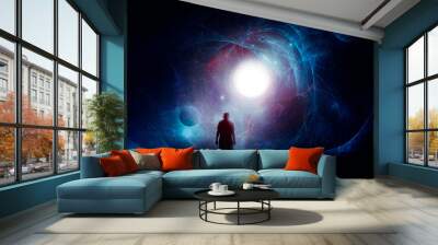 A science fiction concept of a man, back to camera, looking at a bright sun set against a  universe of stars and planets. Wall mural