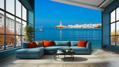 A serene view of the coastal town of Sur in Oman featuring a traditional boat on calm waters under a clear blue sky Wall mural