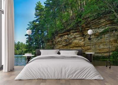 Summer’s day closeup of sandstone cliffs and a lush green forest along the banks of Mirror Lake, near Baraboo, Wisconsin. Wall mural