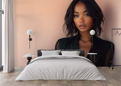 A beautiful non-binary model with medium-length straight hair, wearing a sleek black blouse and jeans, posing gracefully on a light pink background Wall mural